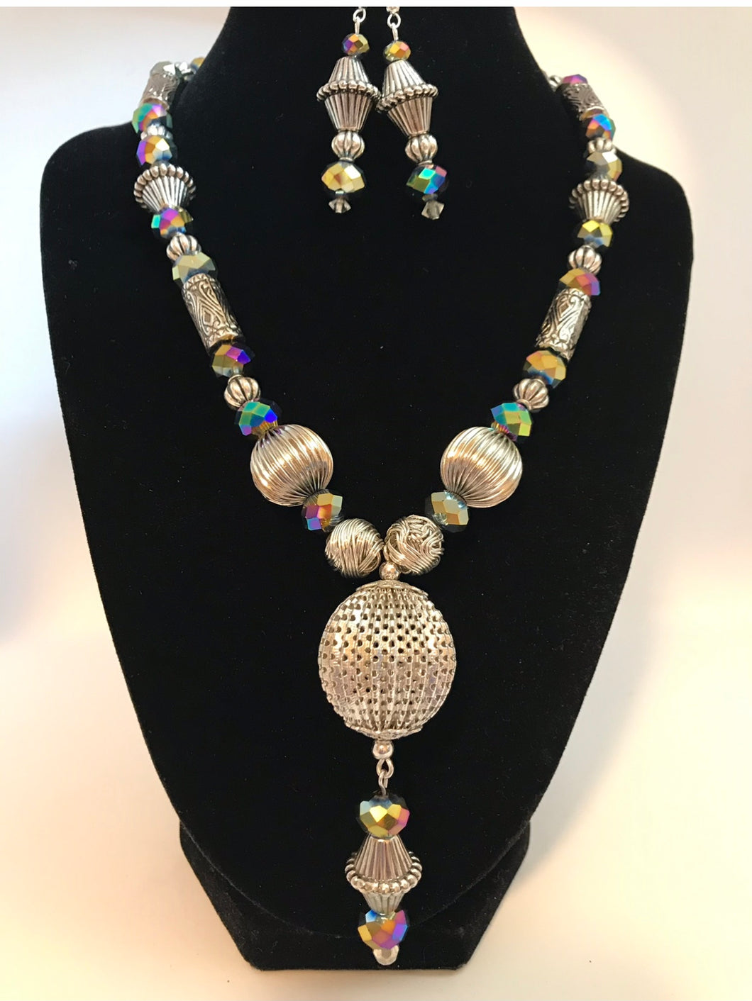 Large metal silver focal piece with assorted novelty metal beads and multi-color irridesent glass faceted beads, with matching earrings.