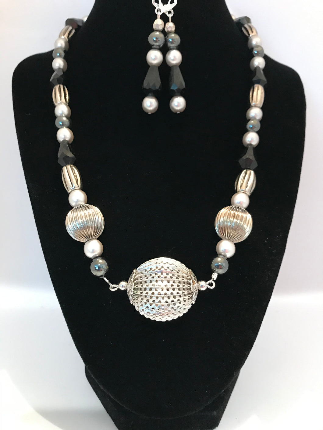 Metal oblong focal pendant with assorted metal, pearl and glass beads, with matching earrings.